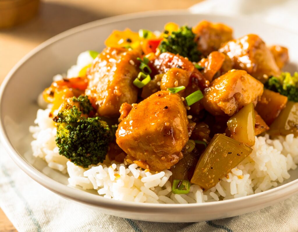 Honey garlic chicken stir fry with vegetables and rice in a white bowl.