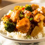 Honey garlic chicken stir fry with vegetables and rice in a white bowl.